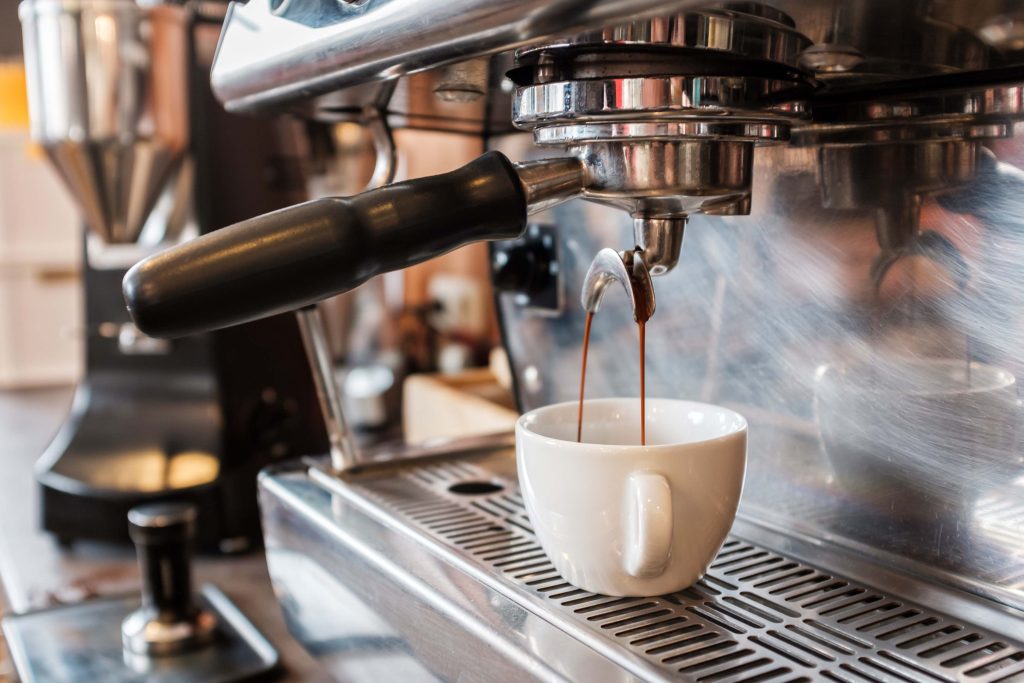 Close-up of an espresso machine pouring coffee into a white cup.